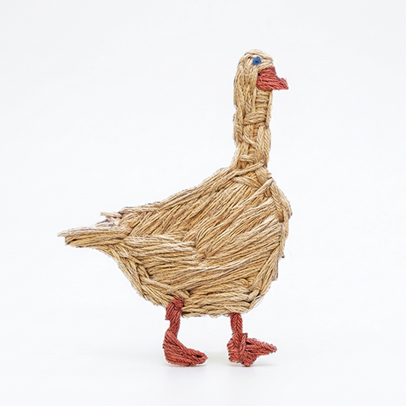 embroidered duck in natural and red thread, textile object with layered stitches on a light background.