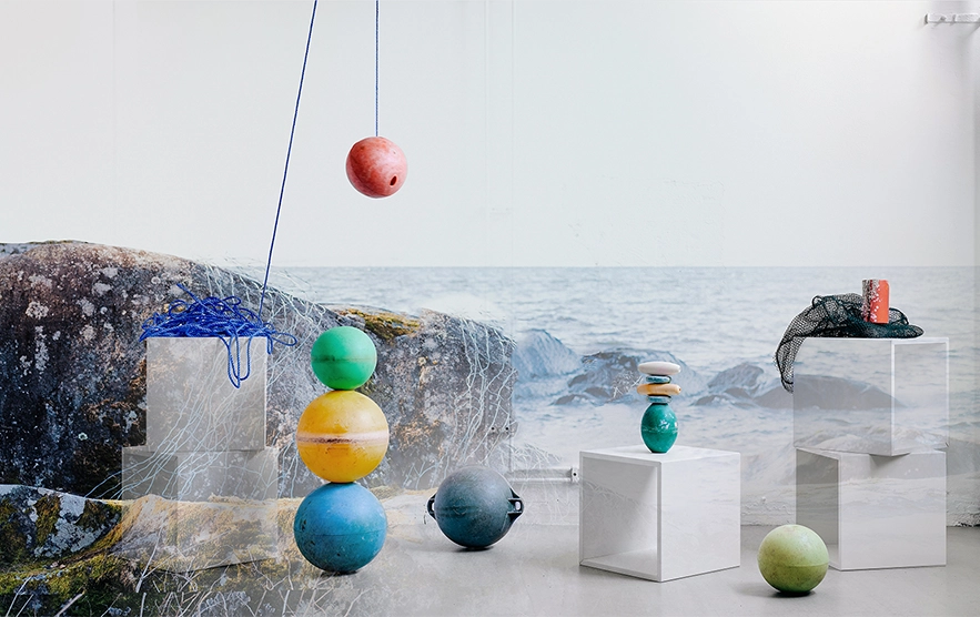 Materials and objects placed on plinths in a studio with a sea view.