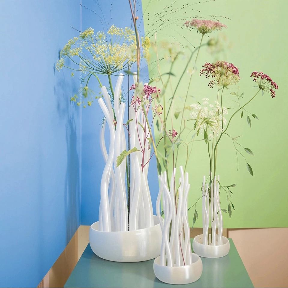 The Träsk vase by Scruffy Little Love, made from recycled sea plastic, shown with a large, natural-looking bouquet placed in a home interior.