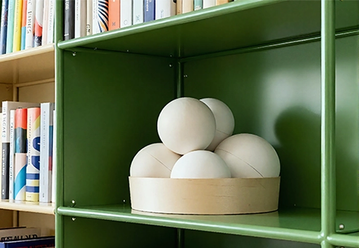 Scruffy Little Love’s NikNak storage containers placed on a green bookshelf, surrounded by books